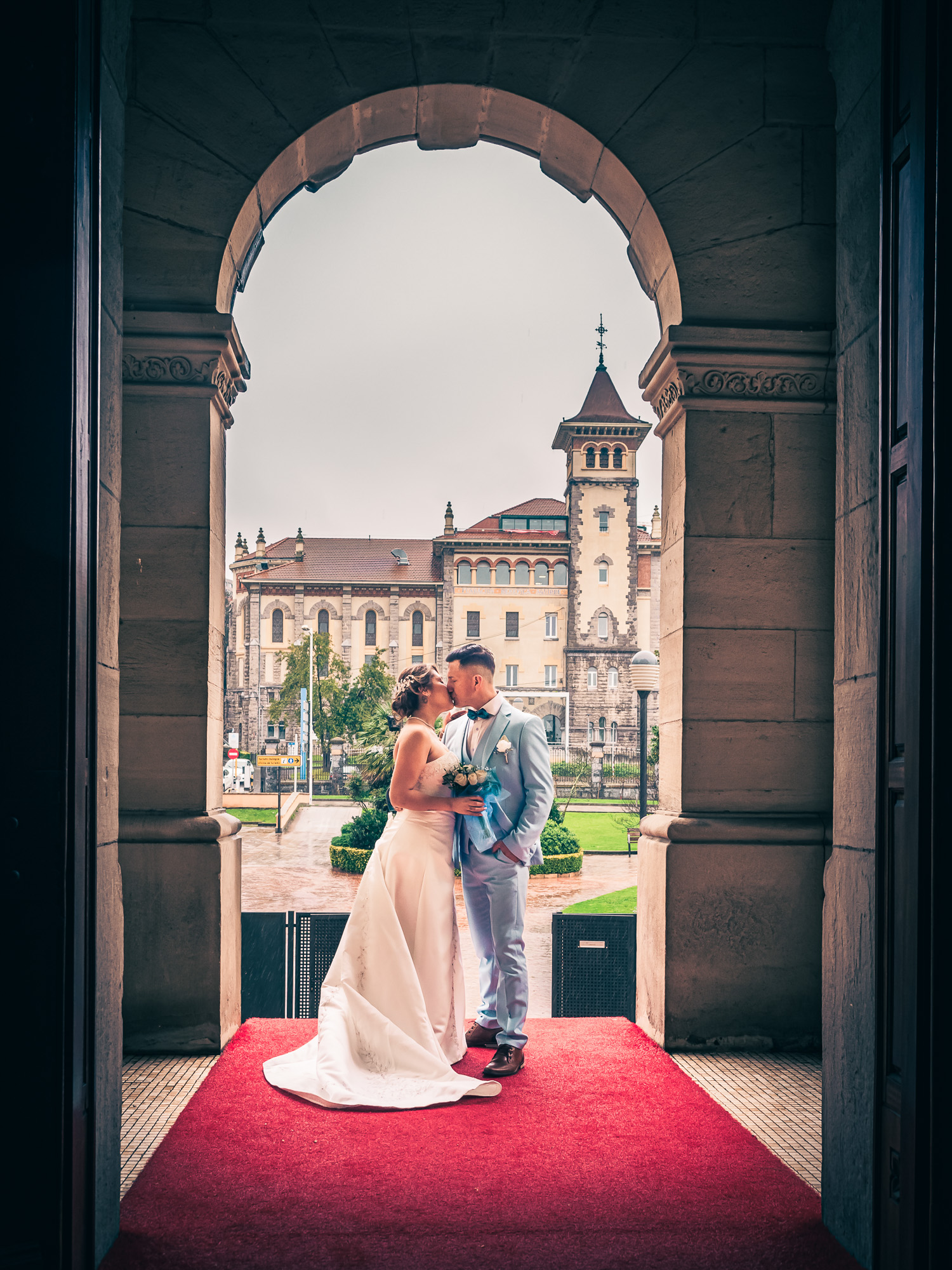 Groom and bride kissing under the arch at the hotel entrance. Wedding